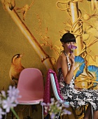 Sitzende Frau mit Blüte in der Hand vor Bildtapete