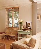 Holzklappstühle unter Fenster und beige Couch im hellen Wohnraum