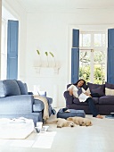 Junge Frau und zwei Hundewelpen in maritimem Wohnzimmer mit zwei blauen 2-Sitzern