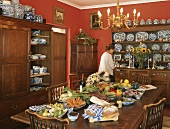 Porzellansammlung in Holzschränken im roten Esszimmer mit Gemüse und Brot auf dem Esstisch