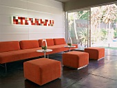Moderne Loungegarnitur in Orange vor offener Schiebetür mit Blick auf den Garten
