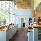 Elegante Vintageküche in Hellblau in einem Loft mit großer Industriefensterfront