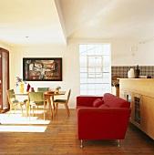 Rotes Sofa in einem Wohnraum mit offener Küche und 50er Jahre Tischgarnitur
