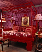 Ein Himmelbett mit rot Lackiertem Holzgestell im Schlafzimmer mit Violetter Wand- und Deckenverkleidung