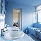Doppelwaschbecken und Badewanne unter Fensterfront im blauen Badezimmer aus