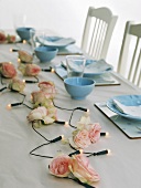 Ein mit Lichterkette und Rosenblüten dekorierter Tisch