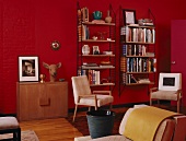 Rotes Zimmer mit schlichten Wandregalen und Polsterstühlen im Stil der 50iger Jahre