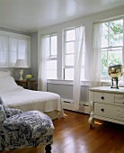 Komfortables Schlafzimmer mit langer Fensterfront und luftigen Chiffonvorhängen