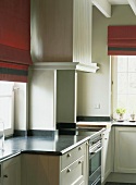 Küchenecke mit roten Raffrollos und Sprossenfenstern