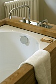 Badewanne mit Holzverkleidung und moderner Armatur