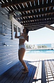 Woman showering on veranda next to swimming pool
