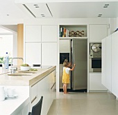Kleines Mädchen öffnet den Kühlschrank in der Küche