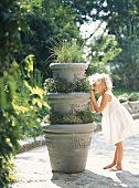 Kleines Mädchen versteckt sich im Garten hinter Blumentöpfen