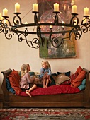 Zwei kleine Mädchen auf Sofa, im Vordergrund Hängeleuchter mit Kerzen
