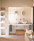 Einladendes, helles Badezimmer mit zwei Waschbecken, verschiedenen Utensilien und integriertem Regal