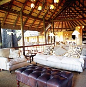 Offener Wohnbereich mit gemütlichem Sofa und Sessel unter einem Reetdach in der Natur