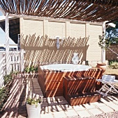 Holzverblendeter Whirlpool im Garten mit Sonnenschutz aus Ästen