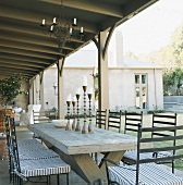 Überdachte Terrasse mit Vintageholztisch und Eisenstühlen