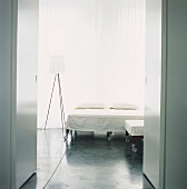 Minimalistischer Schlafraum mit Bett auf Rollen, Fensterfront und Designerstehlampe
