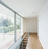 Die moderne Holztreppe erschließt den oberen Wohnbereich mit komplett verglaster Panoramafront und langem Balkon