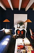 Farbkontraste in Rot- und Blautönen erzeugen Spannung in dem antik eingerichteten Wohnzimmer mit Holzbalkendecke
