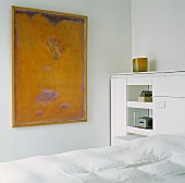 Ein weisses Schlafzimmer mit gelbem Gemälde als Farbtupfer