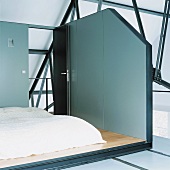 Ein separater, bühnenartiger Schlafbereich im Dachraum eines Lofts mit Stahlrippendecke
