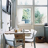 Schöner alter Holztisch mit modernen Aluminiumstühlen in einem Raum mit großer Fensterfront