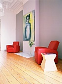 Ein zeitgenössisches Gemälde zwischen zwei roten Ledersesseln in einem Raum mit prunkvoller Stuckdecke