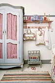 Ein hellblauer Landhauskleiderschrank neben einem rosa Wandregal im Kinderzimmer