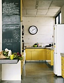 Leuchtend gelbe Küchentheken werten die rohen Betonwände der Küche auf