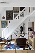 Ein klassischer Wohnraum mit Treppenaufgang zur Galerie wird durch viele Kunstobjekte und Gemälde aufgewertet
