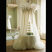 Eine romantisch inszenierte Hochzeitstorte mit federbekröntem Betthimmel aus Tüll