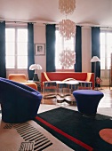 Moderne Polstermöbel und ein transparenter Couchtisch im großzügigen Wohnzimmer mit raumhohen Fenstern