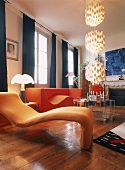 Bunte Designermöbel und eine auffällige Hängeleuchte im Wohnzimmer mit altem Dielenboden und raumhohen Sprossenfenstern