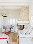 Klassische Polstermöbel in einem hellen Wohnraum mit Rippendecke und Natursteinkamin