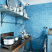 Der antike Wandtisch im komplett blau verfliesten Küchenraum dient als Kochtheke