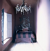 Ein Einzelbett mit aufwendigem Kopfteil und ein traditioneller Kronleuchter in einem orientalischen Wohnhaus