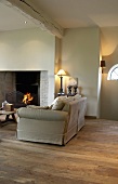 Warmes Licht und ein Kamin verbreiten in dem rustikalen Wohnzimmer mit schönem Holzboden gemütliches Ambiente