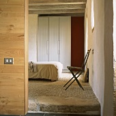 Blick in einen Schlafraum mit rustikalem Steinboden und Holzbalkendecke
