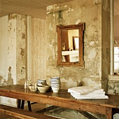 Antiker, rustikaler Holztisch und Spiegel vor einer alten, abgenutzten Wand