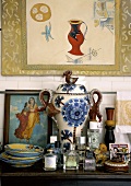 Parfumfläschchen und Keramikwaren auf antikem Wandtisch vor einer Fliesenwand