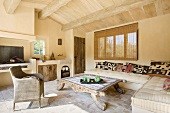 Antiker Couchtisch und Ecksofa im ländlichen Wohnzimmer mit schwerer Holzbalkendecke und Steinboden