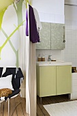 Das kleine, offene Badezimmer mit Vintagewaschtisch ist durch einen Paravent vom Wohnraum getrennt