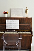 Transparenter Philippe Starck Stuhl vor einem alten Klavier