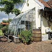 Alte Ziegelsteinterrasse eines kleinen Bauernhauses mit umfunktioniertem Gewächshausanbau