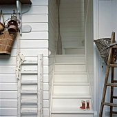 Kleine Gummistiefel auf einer Treppe, die vom weiss verkleideten Eingangsbereich in das Obergeschoss führt
