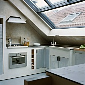 Moderne Einbauküche unter dem Dach mit großem Fenster