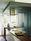 Moderne Küche mit freistehender Herdzeile und abgehängtem Deckenelement mit Abzugshaube