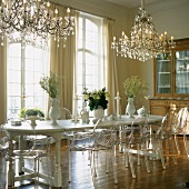 Transparente Louis Ghost Stühle am Landhausesstisch in einem prunkvollen Saal mit Kronleuchtern und raumhohen Fenstern